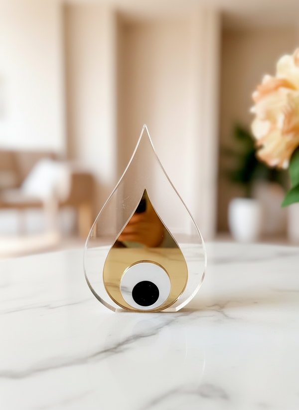 Χειροποίητο επιτραπέζιο γούρι σταγόνα από διάφανο plexiglass με εσωτερικό χρυσό καθρέφτη και μάτι από λευκό–μαύρο plexi, διαστάσεων 10,5×7 cm