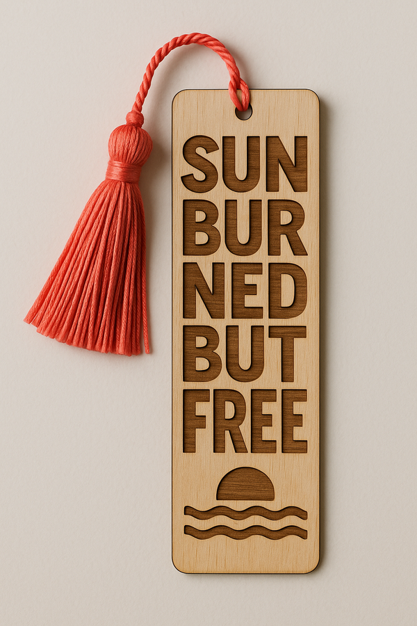 Ξύλινος σελιδοδείκτης με χάραξη “Sunburned But Free” και σχέδιο ήλιου που δύει, με φούντα σε ροζ-κοραλί