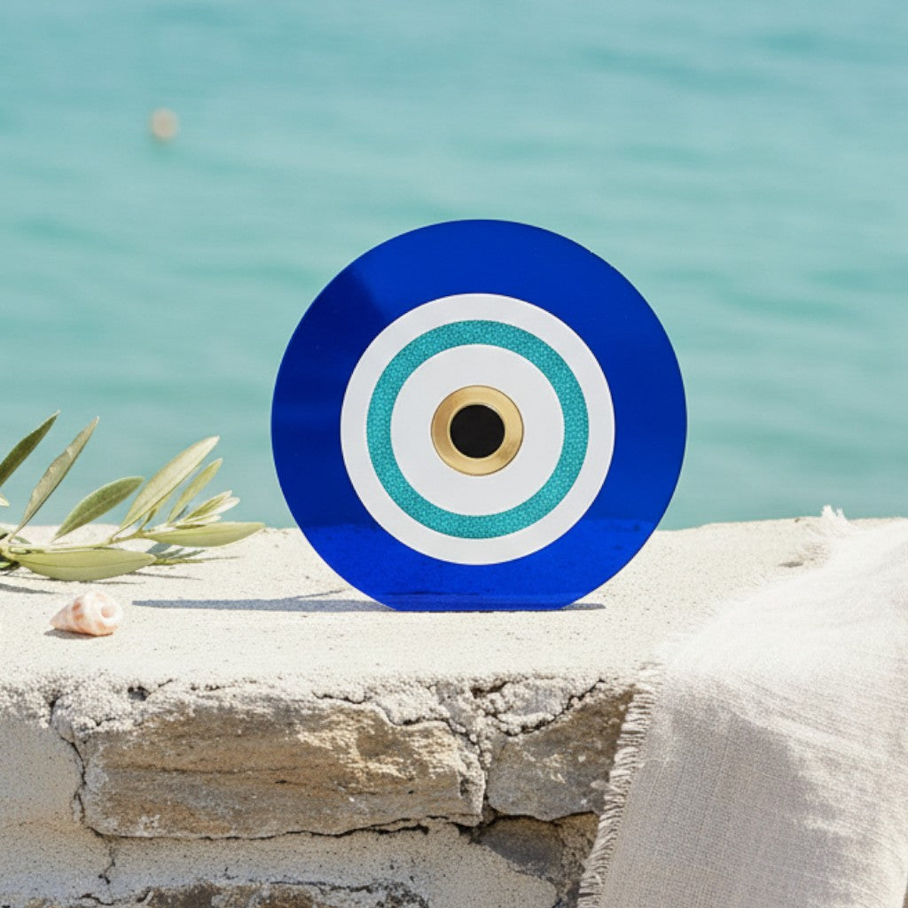 Αυτοστηριζόμενο μπλε ακρυλικό γούρι μάτι με τιρκουάζ λεπτομέρειες σε πέτρινη επιφάνεια δίπλα στη θάλασσα.